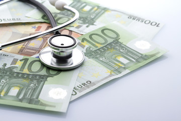 Black stethoscope close-up on top of euro banknotes side view