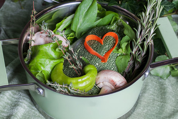 raw vegetables in a saucepan and heart carrots, vegan