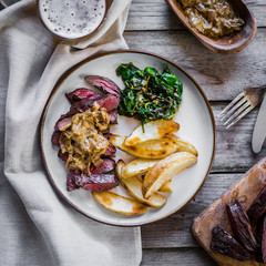 Steak with baked botatoes and green salad on wooden background