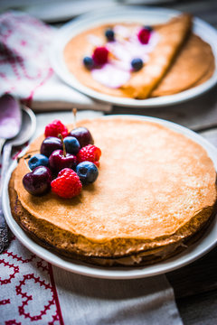 Pancakes with berries on wooden background