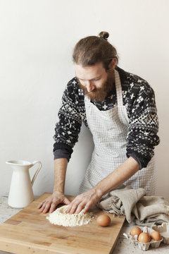 bearded stylish man with apron making dough for fresh pasta