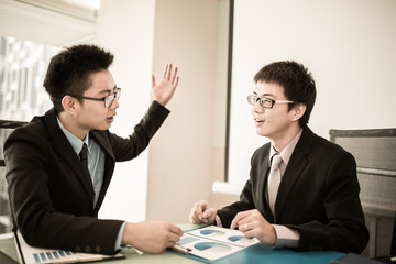 Two Businessmen Having Informal Meeting In Modern Office