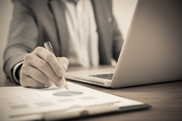 Fototapeta premium Businessman analyzing investment charts with laptop. Accounting