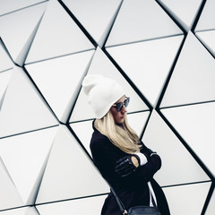 Glamorous blonde standing at the wall. Urban fashion black and w