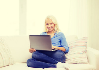smiling woman with laptop computer at home