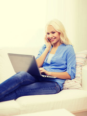 smiling woman with smartphone and laptop at home