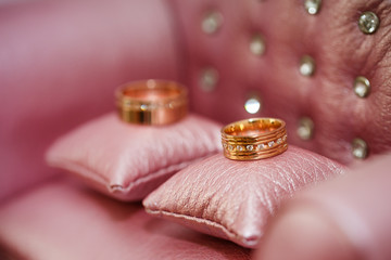 Wedding rings on pink pillows close-up
