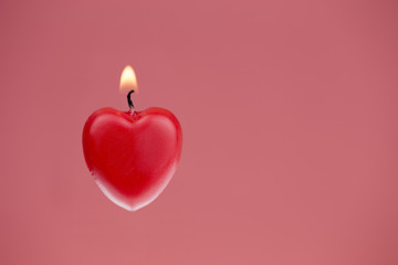 Red heart shaped candle burning, pink textured background - Powered by Adobe