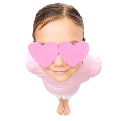 Little girl is holding hearts over her eyes