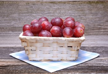 Sweet grapes in basket on wooden background