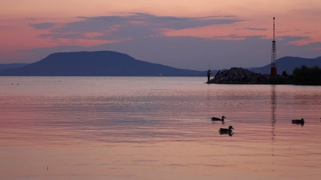Twilight on Balaton lake with Badacsony and turist on the pier