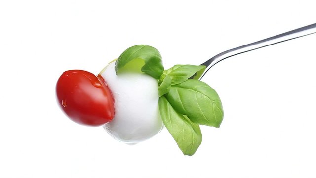 fork tomato basil mozzarella topped with spilled oil isolated on