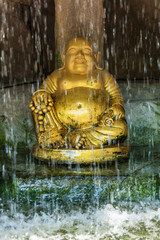 goldener Buddha hinter einem Wasserfall