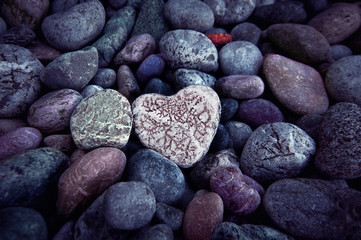 Single  heart on black pebble stones, still life.