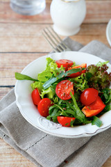 Fresh salad with tomatoes and arugula on a white plate