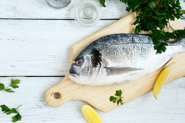 Fresh sea bream and paper on wooden board