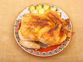 Roasted chicken on a plate with pickles on the canvas.