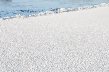 The ice edge on unfrozen river in winter