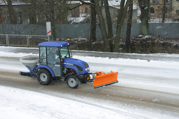 A tractor on a road during a snow storm