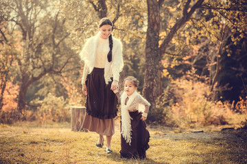 Fototapeta premium Mother and her daughter in vintage clothes in autumn