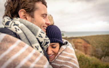 Young couple laughing outdoors under blanket in a cold day - Powered by Adobe