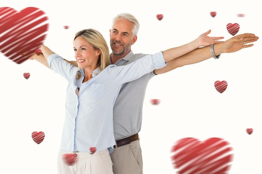 Composite image of happy couple standing with arms outstretched