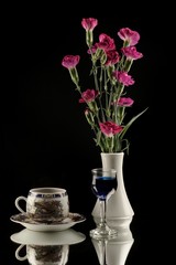 Obraz na płótnie Canvas Purple carnations in white vase and coffe cup