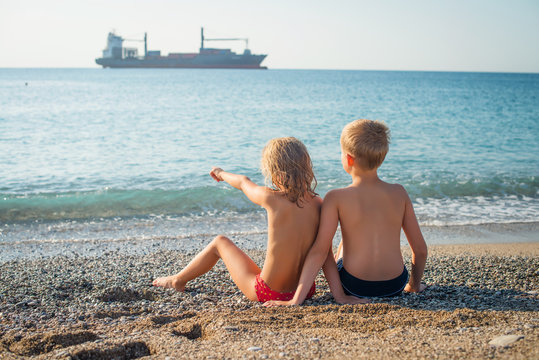 Happy Children At The Beach Looking At The Ship.