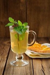 Mint tea and toasts with orange marmalade on wooden background