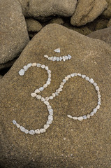 Symbol Om aus großen Kieselsteinen auf  Felsen