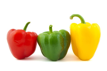 Close up of green, red and yellow fresh peppers on white