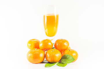 Pile of oranges with juice in glass on white background