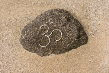 Fototapeta na wymiar Symbol Om aus kleinen Kieselsteinen auf Felsen