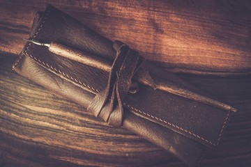 Quill pen with leather case on wooden background