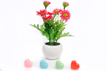 Red flowers in white flower pot with heart, artificially