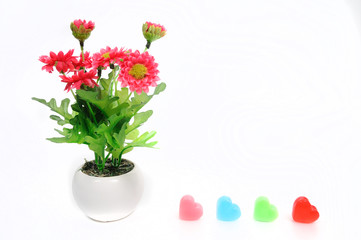 Red flowers in white flower pot with heart, artificially