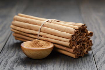 bunch of cinnamon sticks tied with twine and powder in bowl