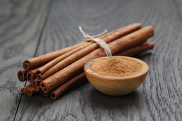 bunch of cinnamon sticks tied with twine and powder in bowl