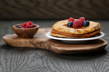 Pancakes with berries and maple syrup, on wooden table