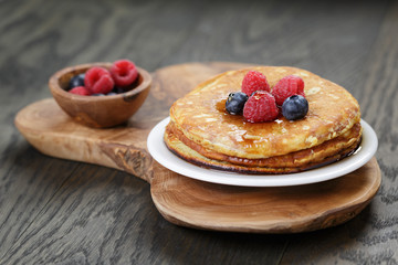 Pancakes with berries and maple syrup, on wooden table