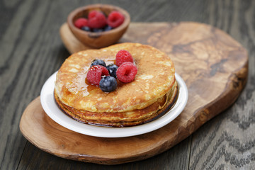Pancakes with berries and maple syrup, on wooden table