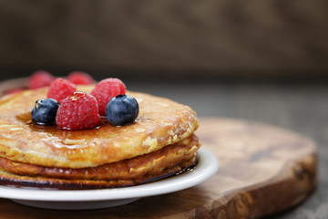 Pancakes with berries and maple syrup, on wooden table