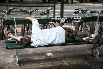 senzatetto ubriaco sdraiato su una panchina