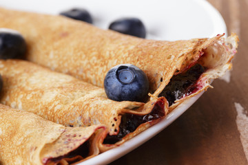 homemade blinis with blueberries and jam, on wooden table