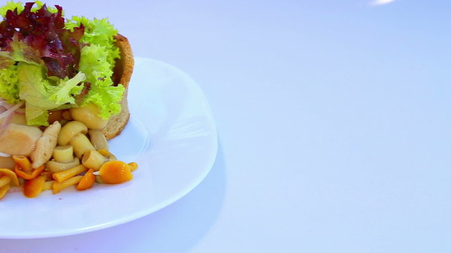 A dish of mushrooms and green salad with onions.