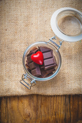 Chocolate and heart in a jar on a wooden background on the day o