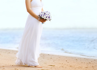 Fototapeta na wymiar Beautiful bride with wedding bouquet outdoors on the coast sea