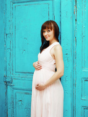 Fototapeta premium Lovely beautiful pregnant woman in dress against the colorful ba