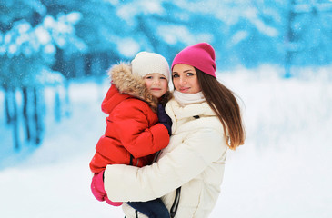 Fototapeta premium Happy mother and child together in snowy day against the snowfla