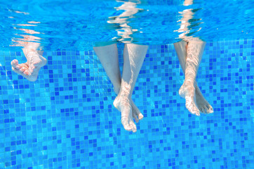 Funny underwater family legs in swimming pool on vacation